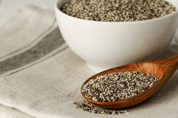 Chia seeds in a bowl with wooden spoon