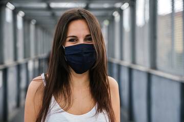 Portrait of beautiful woman on iron bridge in the summer in the city with face mask for protection...