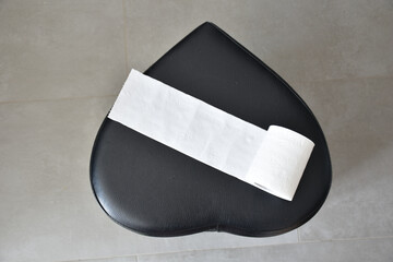 top view of a black heart and toilet paper on a gray background