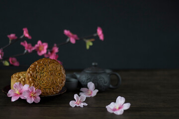 Traditional Baked Mooncake on Dark Background. Mooncakes with Sakura Flowers. Mooncake side view with Copy Space.