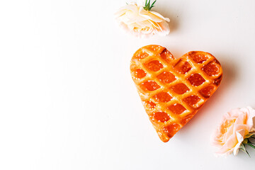 Heart shaped cookie with jam and with two fine pink roses on a white background. heart-shaped cake...