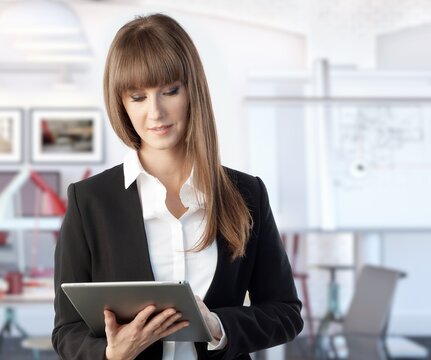 Happy white young businesswoman working with large business tablet. Woman in architect office.
