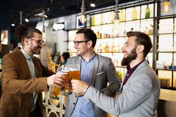 Young businessmen are drinking beer, talking and smiling while resting at the pub