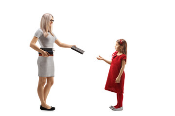 Full length profile shot of a blond woman giving a book to a girl in a red dress