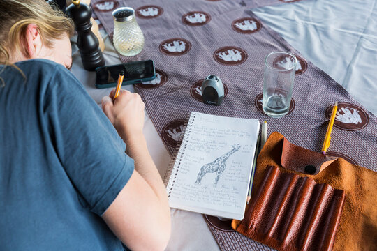 A thirteen year old girl writing in her journal, tented camp, Botswana