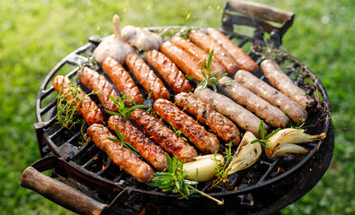 Grilling sausages sprinkled with herbs and spices on a cast iron grill outdoor,  close up view