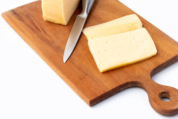 on a white background. No isolation. A small piece of cheese is cut into wedges. And a kitchen knife Close-up.