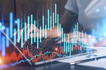 Businesswoman typing on computer in office. Fiancial graph hologram. Double exposure.