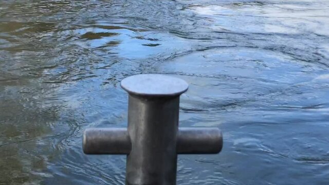 Close up of the Waikato River flowing gently passed the boat anchor capstan on a bright day in Hamilton New Zealand