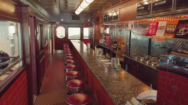 View into an empty nostalgic old fifties Diner with lots of signs and a bar and stools