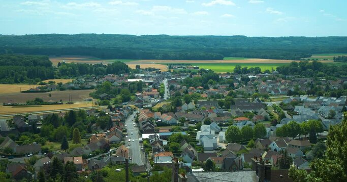 Elevated view of a small town in France countryside with highway passing through middle of village, sunny day