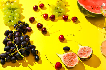 Grapes, a bottle of wine and different fruits on a yellow background. The concept of harvesting, fun and celebration in Italy and Spain. Photo in hard light. High quality photo