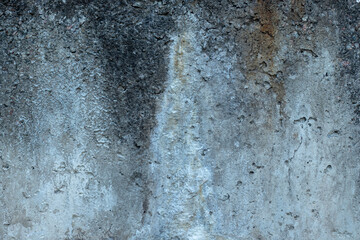 Old concrete gray wall of a building with cracked moss and flood marks. Close-up.