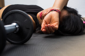 Close up photography of young woman resting after doing exercise at gym, supports the arm on his head, concept of headache.