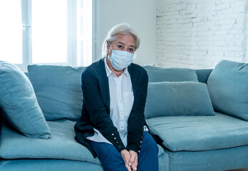 Depressed senior widow woman with protective mask alone at home feeling sad and missing family