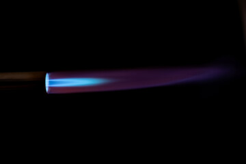 Gas burner with blue fire flame at black background