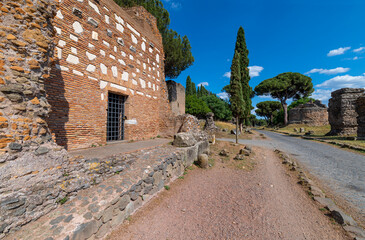 Perspective view of the brick tomb on the Via Appia Antica, Rome. The road was the most important of the Roman Empire, remains of other tombs, rich vegetation, maritime pines, cypresses.