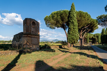 Fototapeta na wymiar Brick sepulcher on the Via Appia on a sunny day. Regina Viarum was one of the most important roads of the Roman Empire, a panorama of Roman castles, rich vegetation, maritime pines, cypresses.