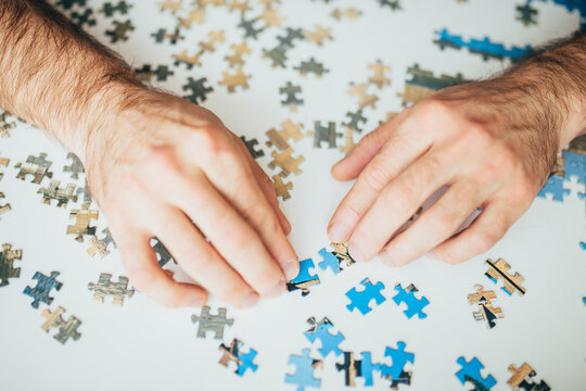 Hands sorting through the pieces of the puzzle in search of the necessary solution to the graphic puzzle