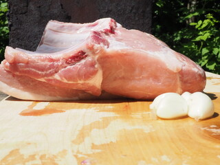 pork loin on the bone with garlic on a wooden Board. cooking in nature. against the background of...
