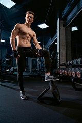 Shirtless bodybuilder posing in gym.