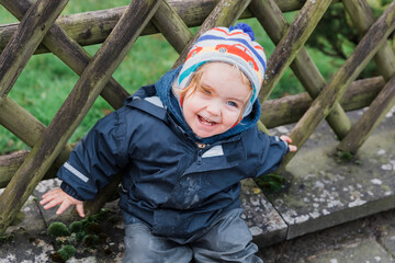 Happy toddler girl sitting in front of wooden fence