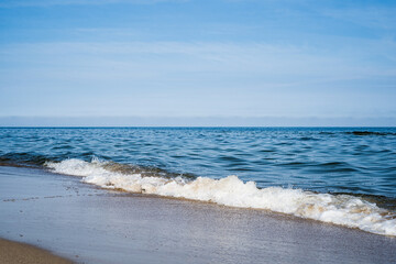 Beautiful waves crashing on a sandy beach by the Baltic Sea in Poland
