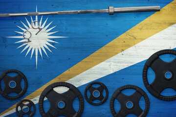 Marshall Islands gym concept. Top view of heavy weight plates with iron bar on national background.