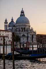 Fototapeta na wymiar The Basilica di Santa Maria della Salute at dusk along the Venice docks with Gondola boats 