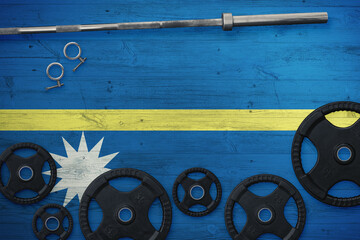 Nauru gym concept. Top view of heavy weight plates with iron bar on national background.