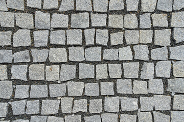 Granite cobblestone and small gravel pavement background. Full frame of irregular cobble. Natural stone textured background
