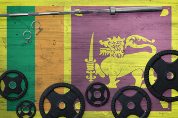 Sri Lanka gym concept. Top view of heavy weight plates with iron bar on national background.
