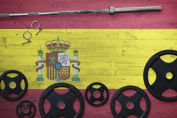 Spain gym concept. Top view of heavy weight plates with iron bar on national background.