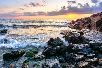 Fototapeta na wymiar beach of the sea at sunset. wonderful scenery with stones in the water. beautiful clouds above the sun and horizon. concept of zen mood and spirituality