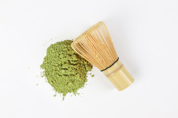 Matcha, green tea powder and bamboo whisk on white