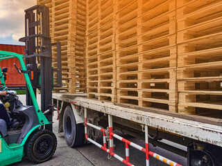 Worker driving forklift to loading and unloading wooden pallets from truck to warehouse cargo...