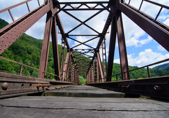 Railway bridge over river in moutains. Old rusty railway bridge.