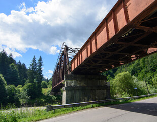 Fototapeta premium Railway bridge over river in moutains. Old rusty railway bridge.