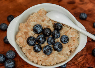Oatmeal with blueberries. Healthy breakfast. Wooden background. Top view. Selective soft focus. Shallow depth of field.