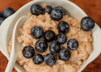 Oatmeal with blueberries. Healthy breakfast. Wooden background. Top view. Selective soft focus. Shallow depth of field.