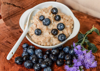Oatmeal with blueberries. Healthy breakfast. Wooden background. Top view. Selective soft focus. Shallow depth of field.