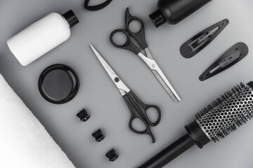 Professional hair dresser tools with copy space. Hair stylist equipment set on gray background. Scissors, brush, hairbrush, balm flat lay top view.
