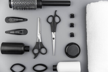 Professional hair dresser tools with copy space. Hair stylist equipment set on gray background. Scissors, brush, hairbrush, balm flat lay top view.