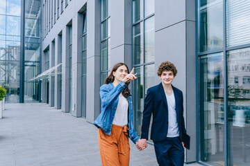 Image of kind students couple man and woman looking at camera, smiling at urban background outdoors. Concept Education lifestyle. Close up portrait.