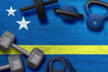 Curacao sports club concept. Top view of heavy weight plates with iron bar on national background.