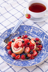 dessert with fresh berries in a blue vintage plate. Sweet roll.
