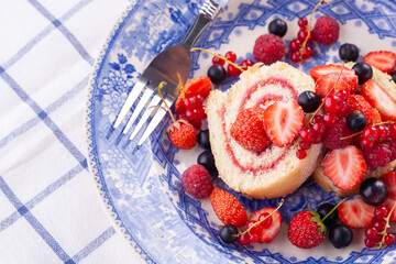dessert with fresh berries in a blue vintage plate. Sweet roll.