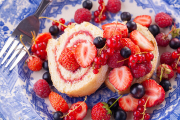 dessert with fresh berries in a blue vintage plate. Sweet roll.