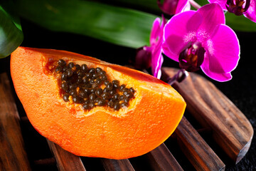Papaya, fruta fresca tropical con semillas y Orquídeas