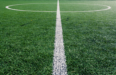 The centre of soccer field with artificial green grass and white lines near the school. Amateur football field. Sunny summer day